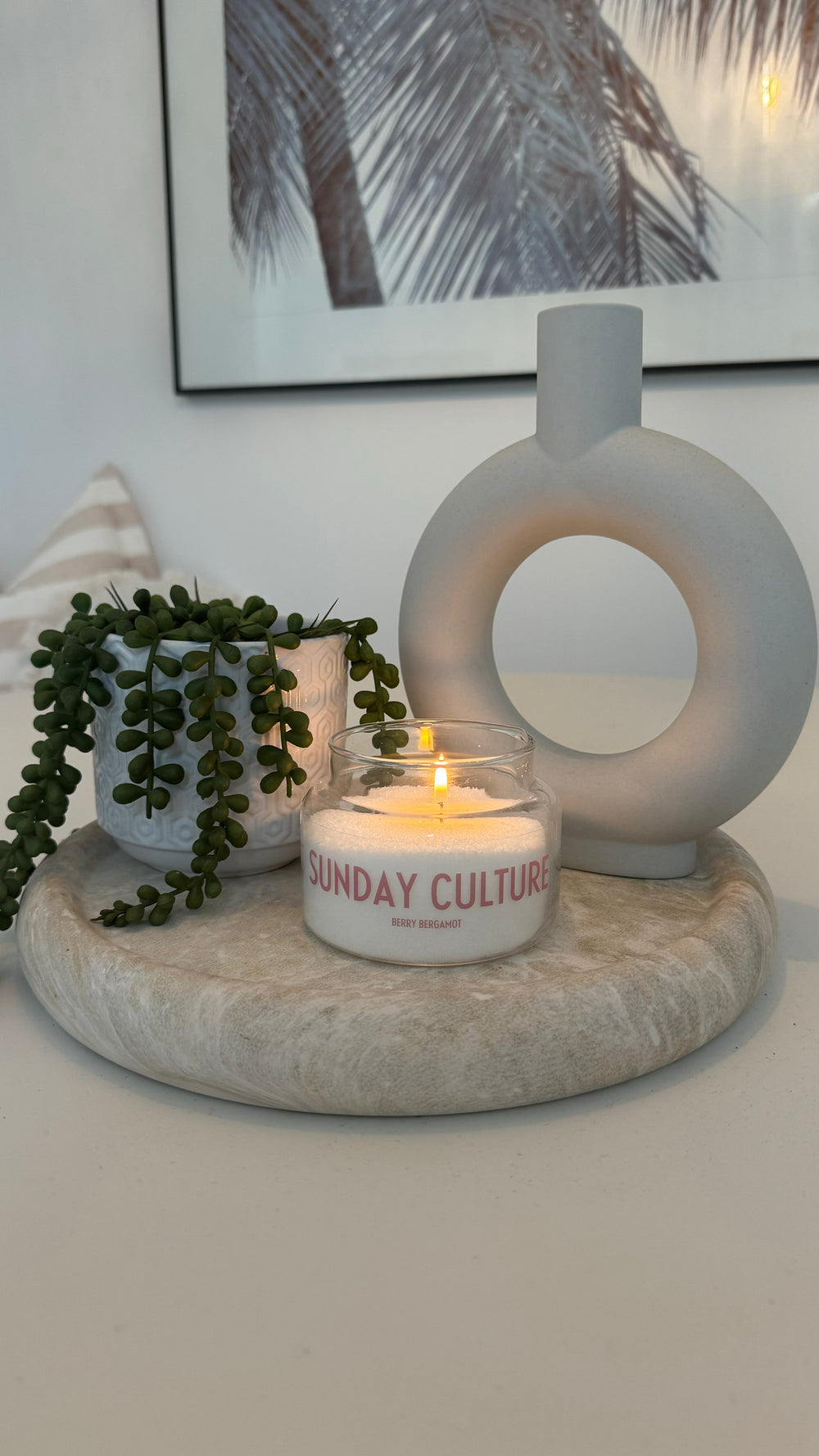 Candle with 'Sunday Culture' text on a stone surface with decorative elements.