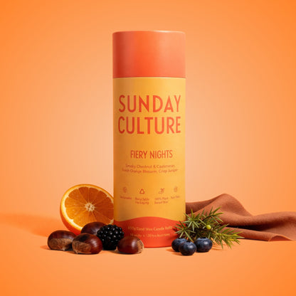 Sunday CultureFiery Nights candle on an orange background with fruits and a cloth.